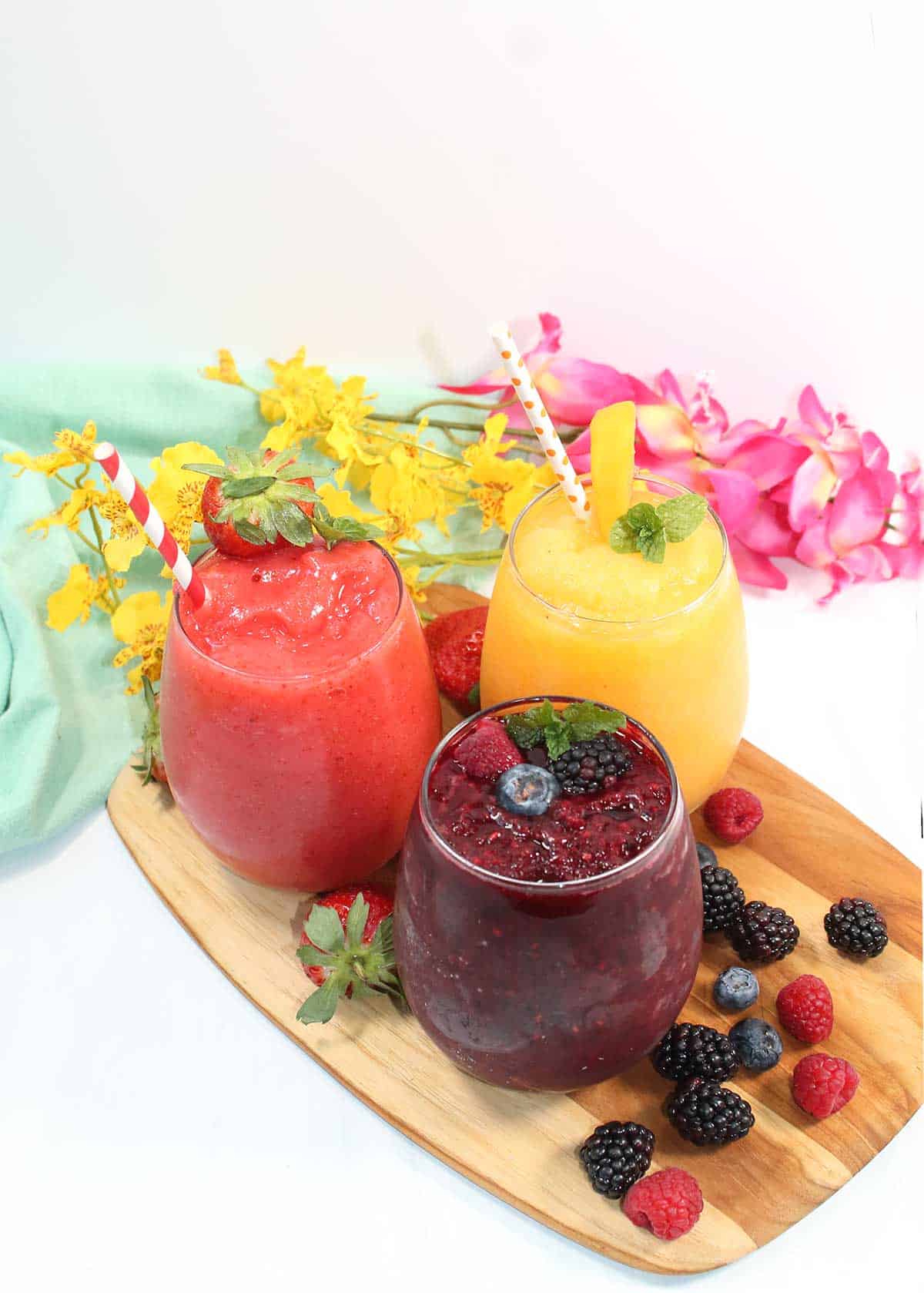 Three wine slushies with different flavors on wooden tray.