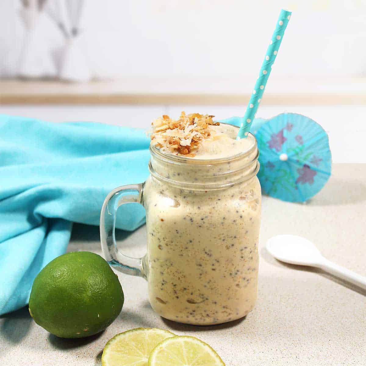 Coconut Smoothie in mason jar with straw and umbrella in back.