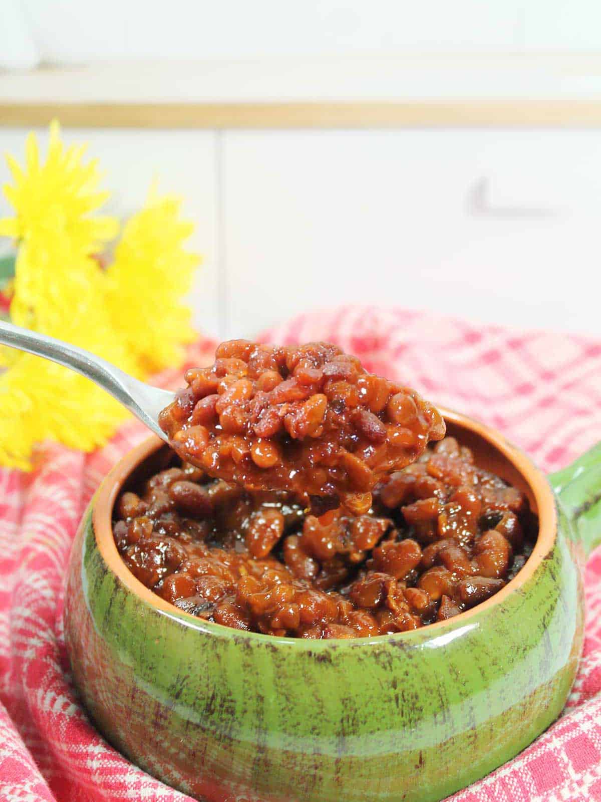 Spoonful of finished baked beans over green bowl.