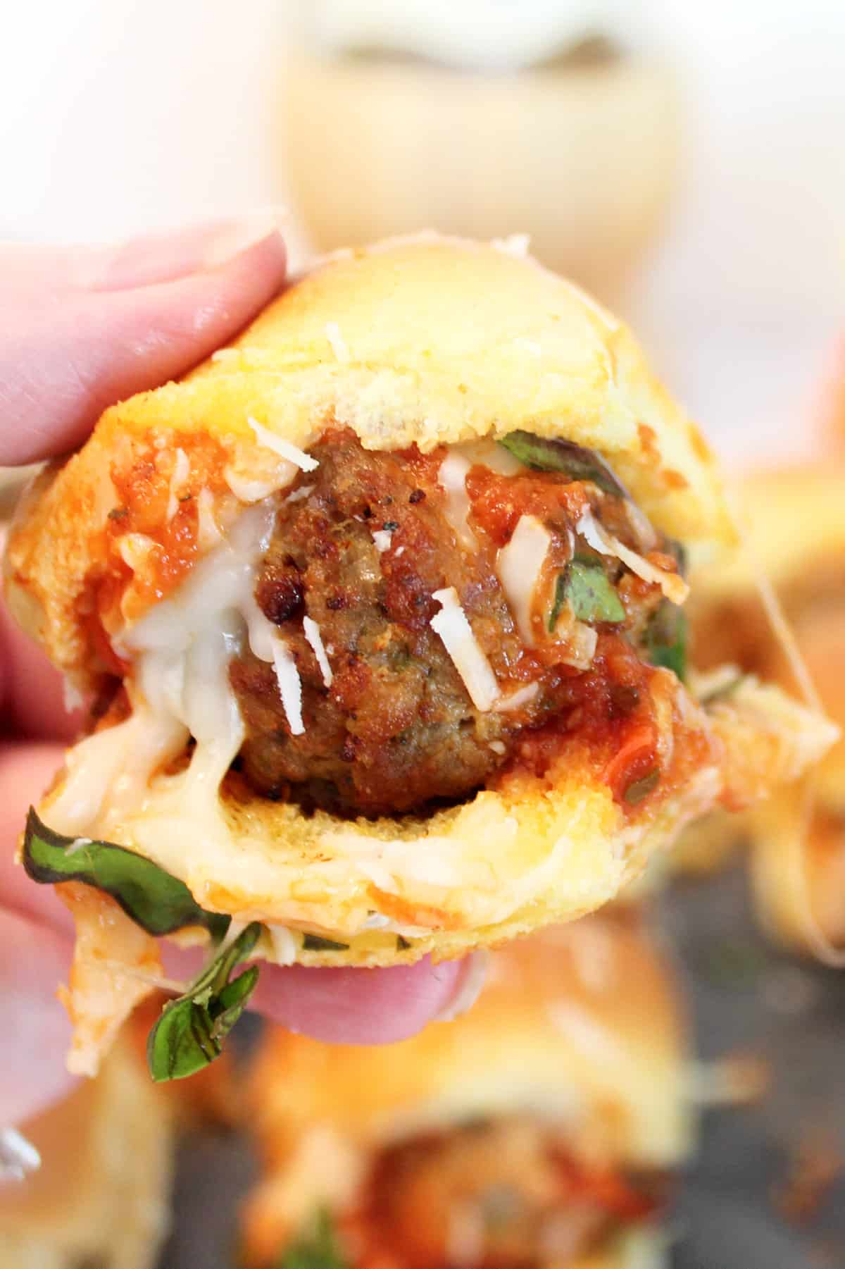 Holding a meatball slider over a trayful of sliders..