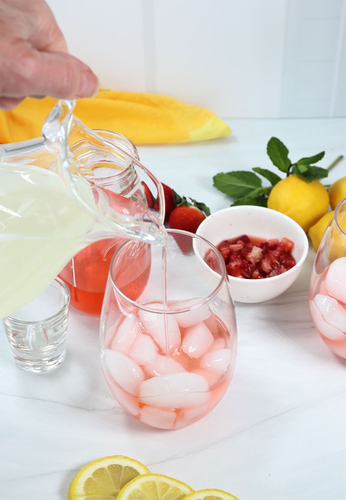 Pouring lemonade into iced filled glass with strawberry vodka.
