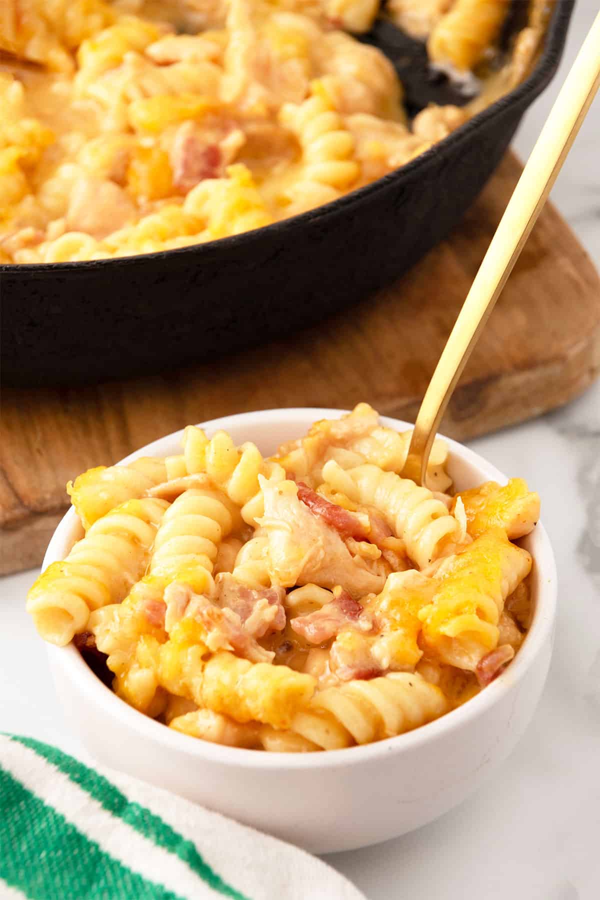 Chicken Bacon Mac and Cheese bowlful in front of skillet.