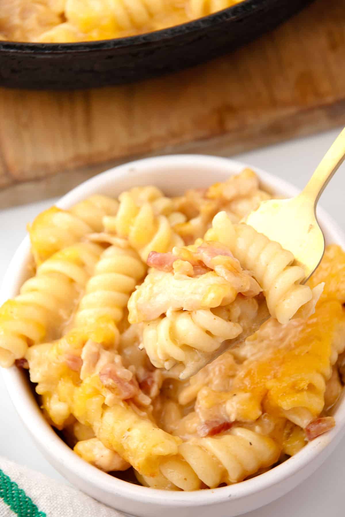 Mac and cheese on fork above bowl.