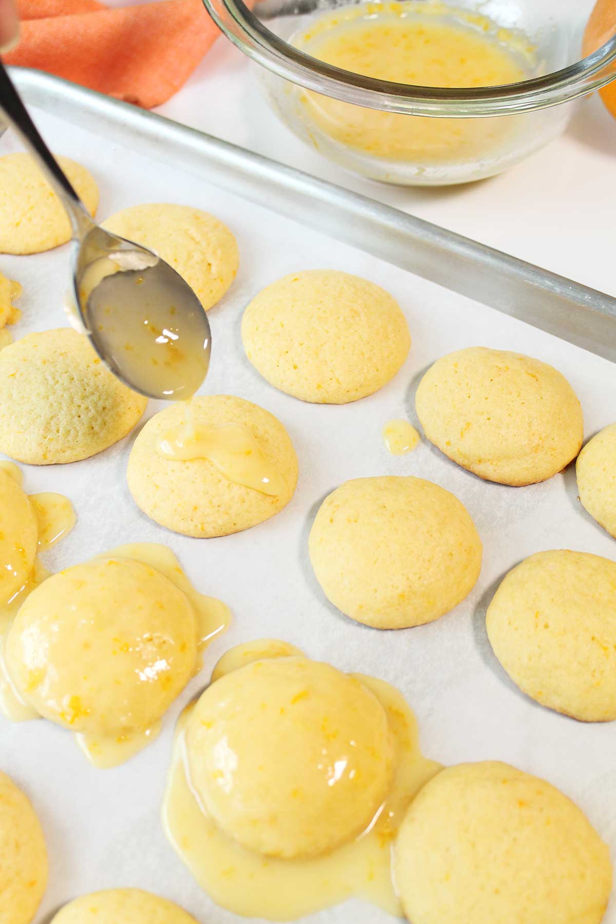 Drizzling the orange glaze over the cookies.