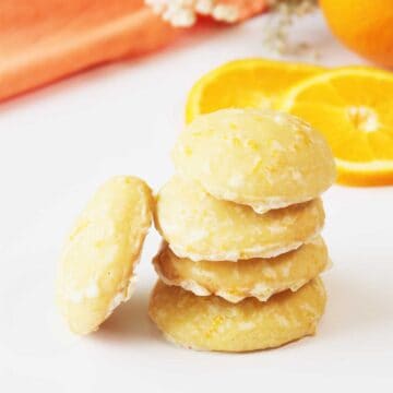 Stack of orange cookies with orange icing.