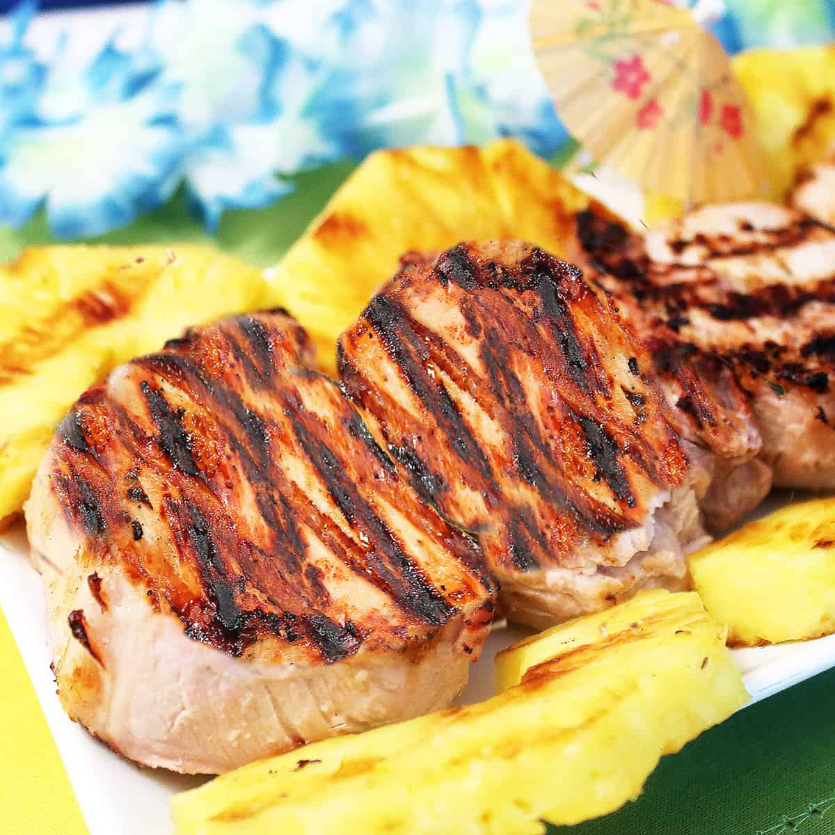 Platter of grilled pork chops with pineapple rings.
