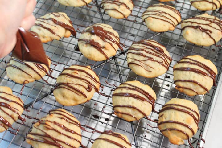 Drizzling chocolate on top of cookies.