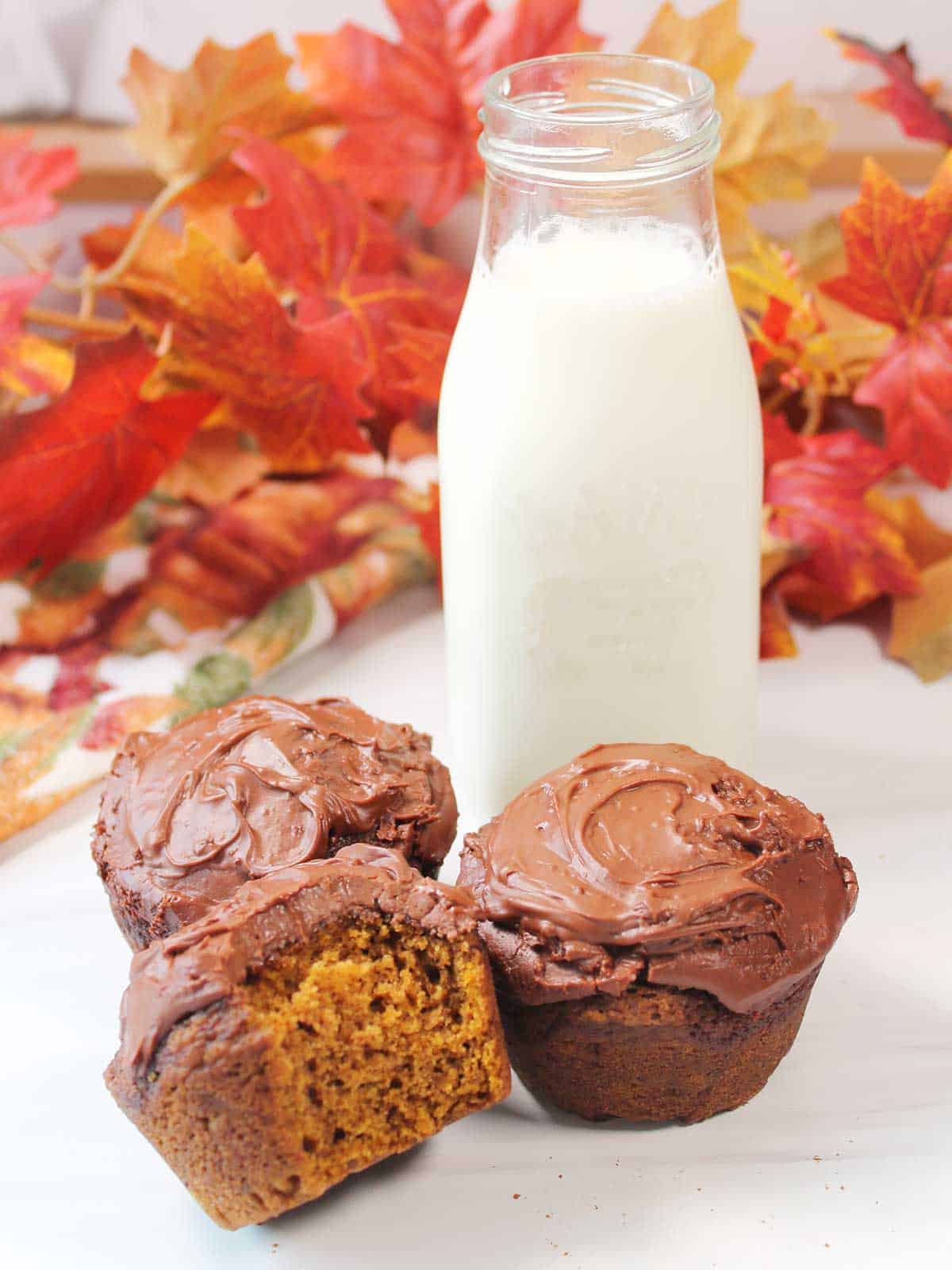 Three pumpkin Nutella muffins by milk bottle with bite out of one.