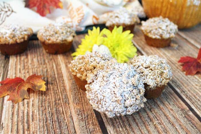 pumpkin muffins on wooden table with fall leaves around.