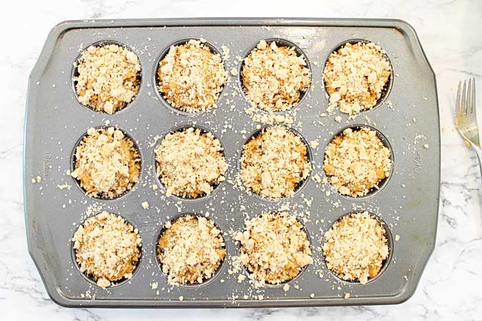 pumpkin muffins with crumbs in cupcake pan ready for oven.