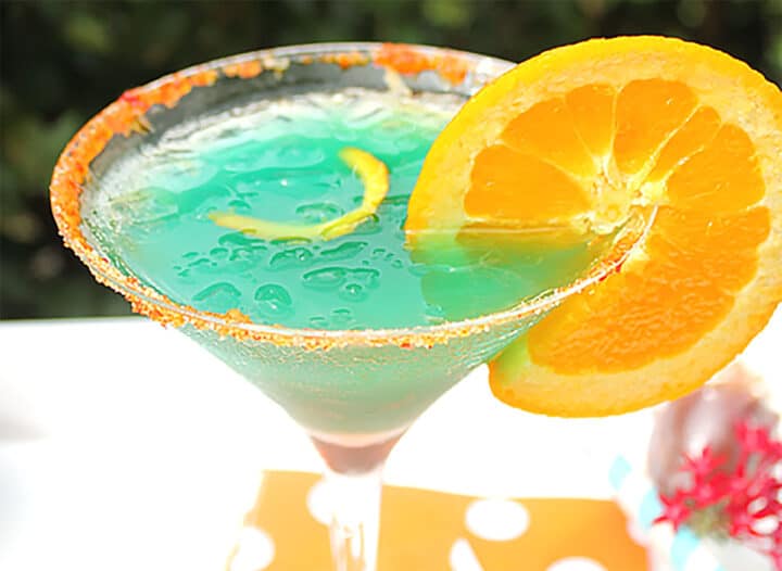 Blue curacao cocktail with orange garnish closeup.
