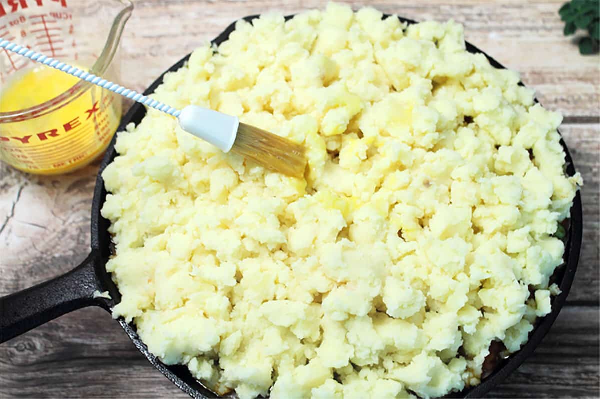 Buttering tops of mashed potatoes.