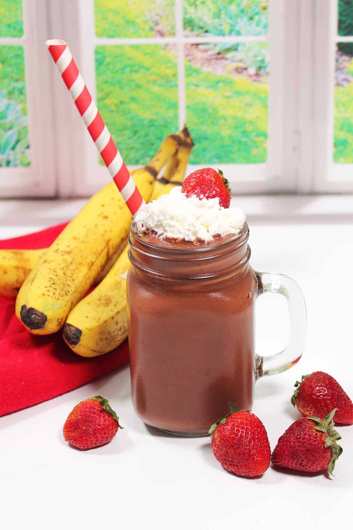 Finished smoothie with straw in front of window.