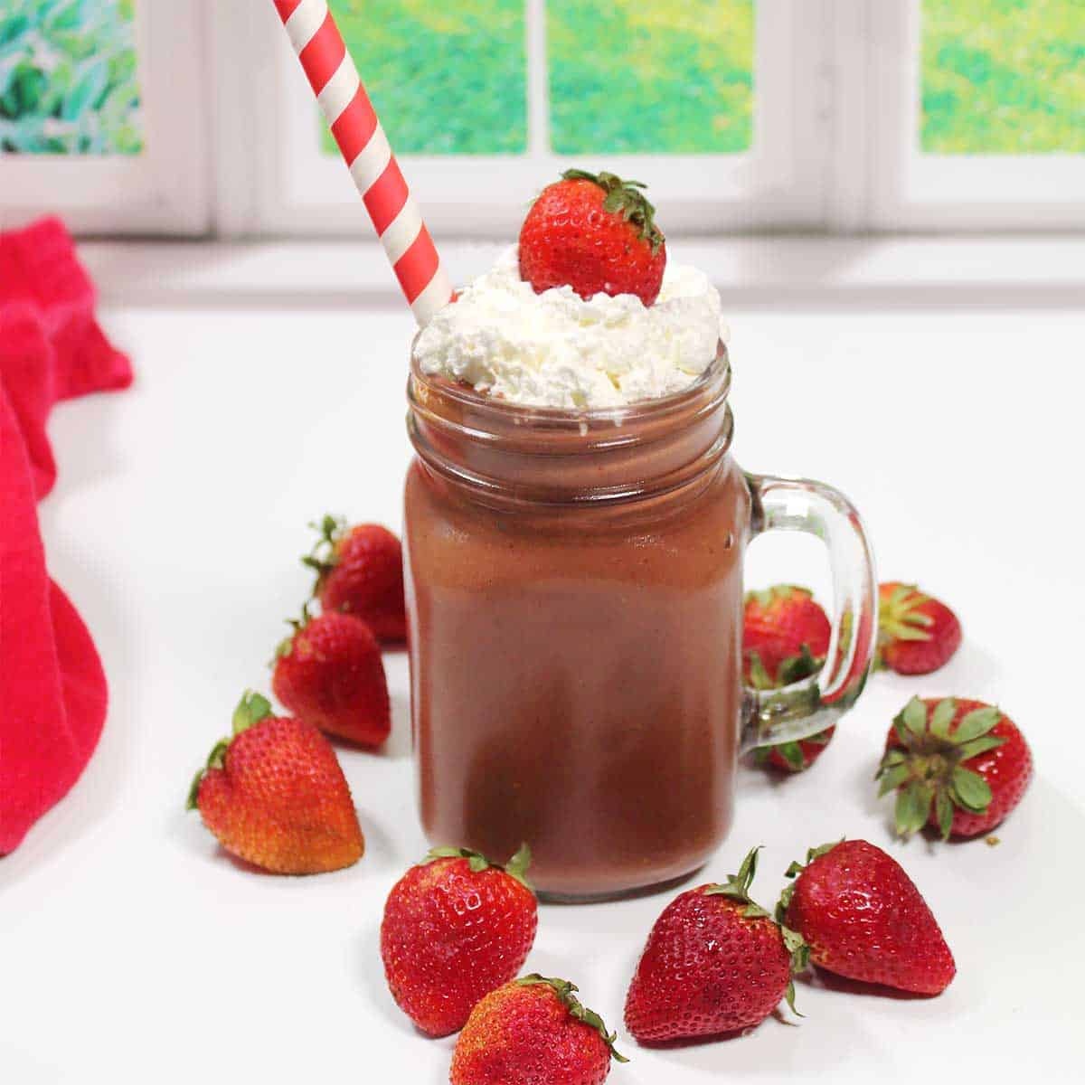 Garnished chocolate strawberry smoothie surrounded by strawberries.