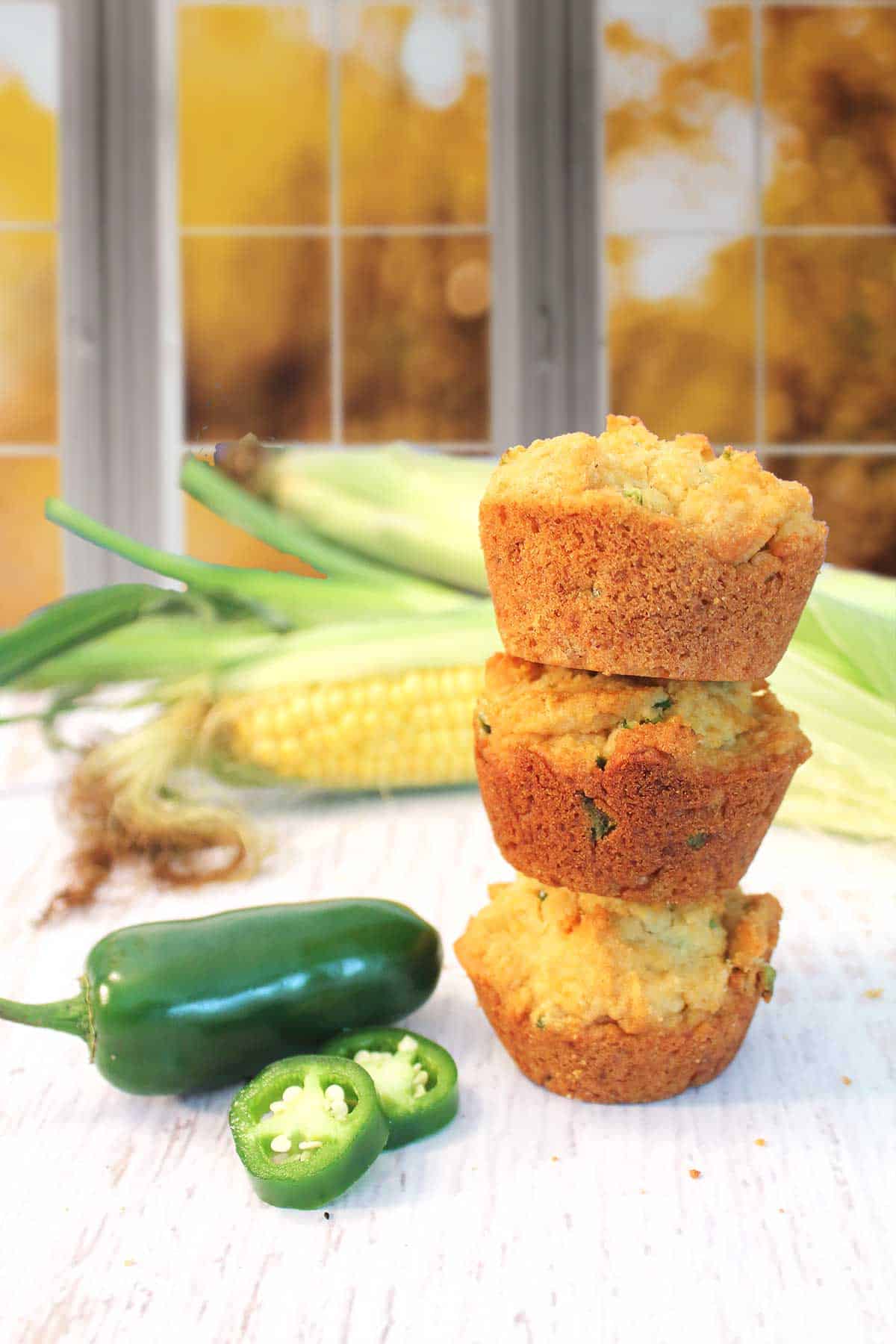Stack of jalapeno cornbread muffins with corn on the cob and jalapenos.