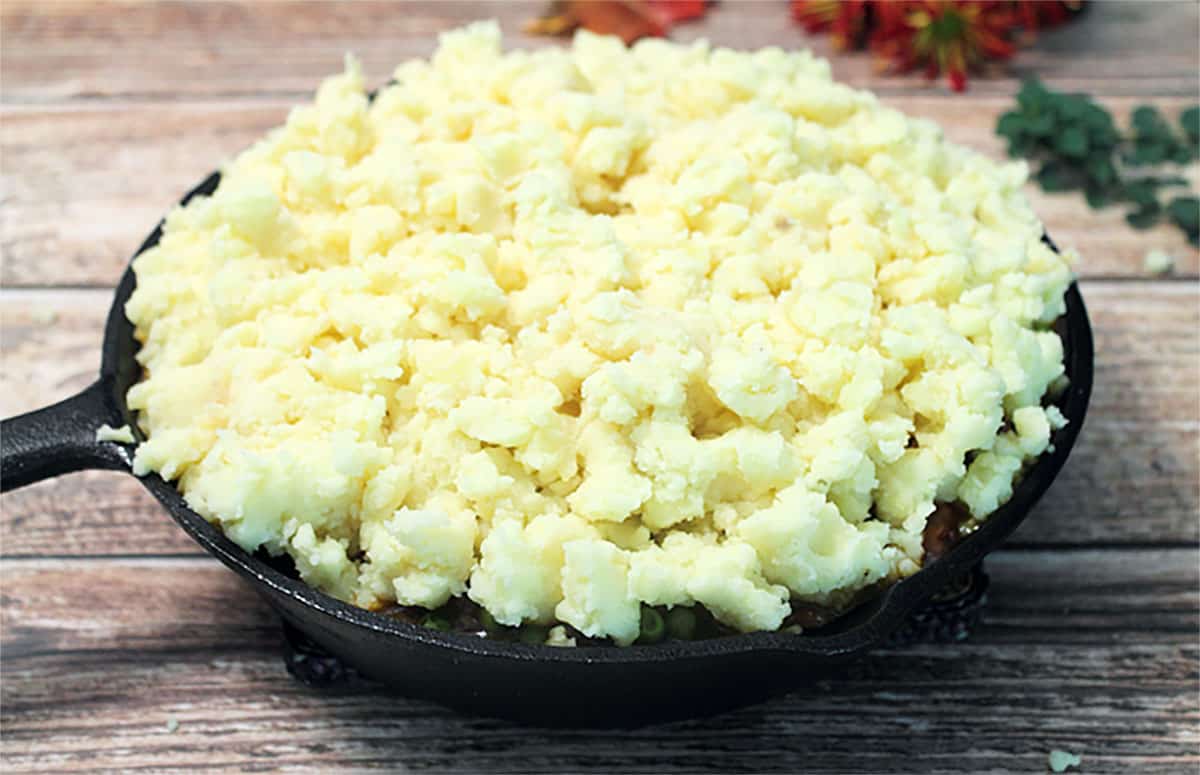 Showing mounds of potatoes on top of beef vegetable mixture.