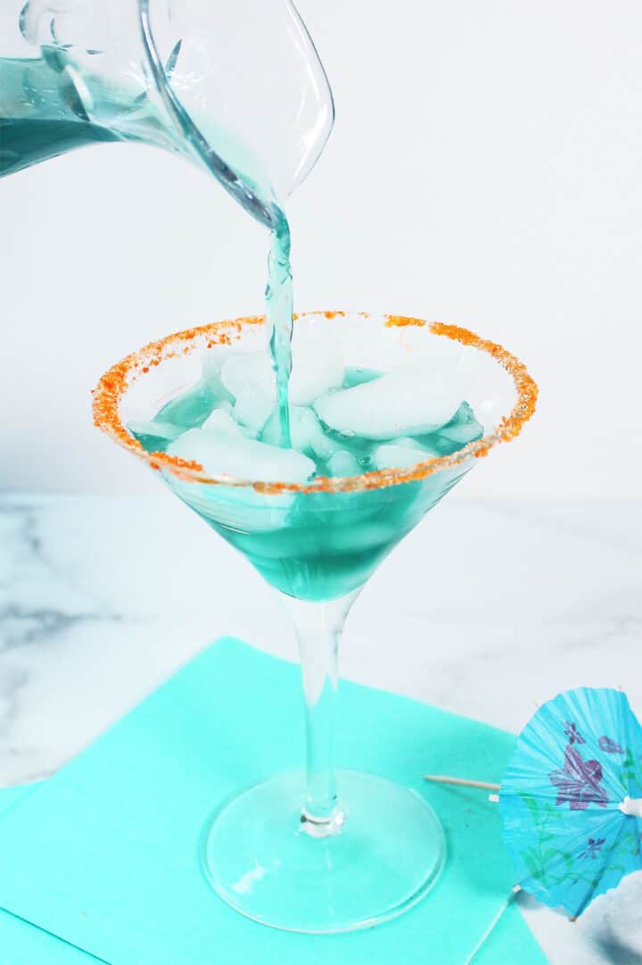 Pouring cocktail into garnished martini glass.