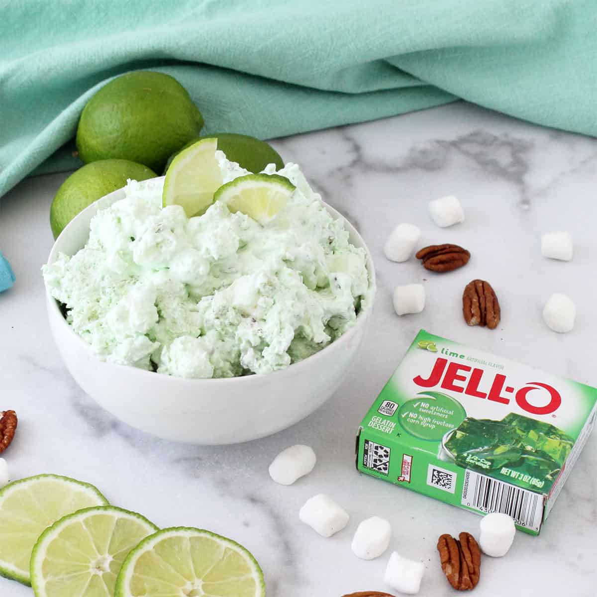 Bowl of green fluff in white bowl with limes in back.