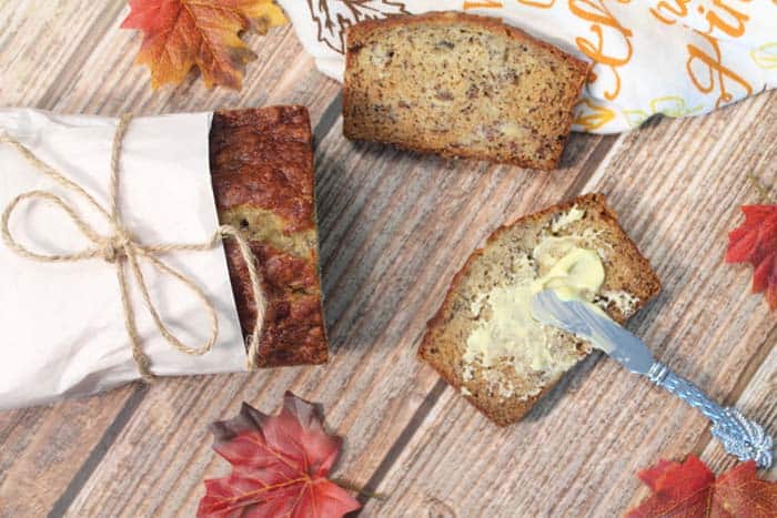 Sliced moist banana bread with honey butter schmear on wooden table.