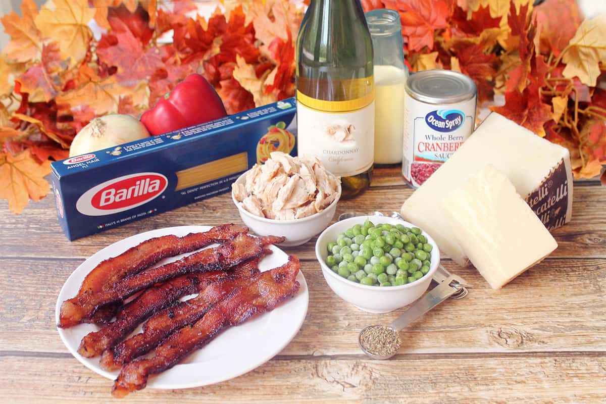 Ingredients for turkey pasta with cranberry cream sauce on wooden table.