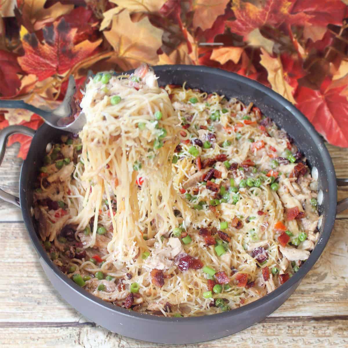 Lifting turkey pasta out of skillet with pasta tongs.