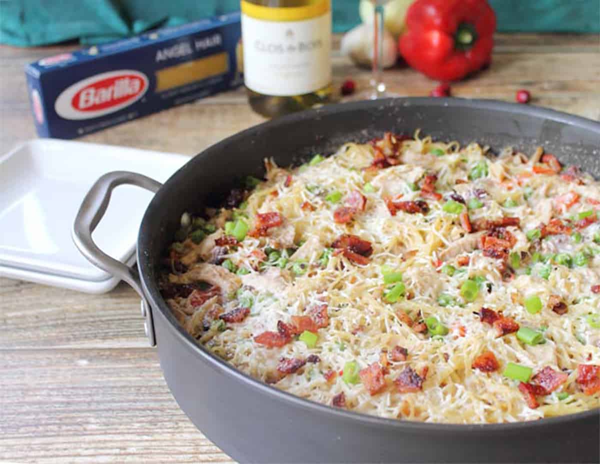 Partial view of one pot meal in skillet with ingredients in back.