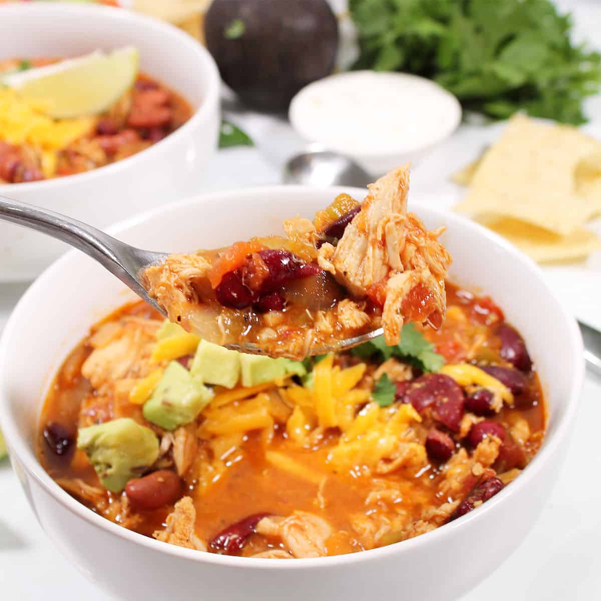 Spoonful of chili over bowl.