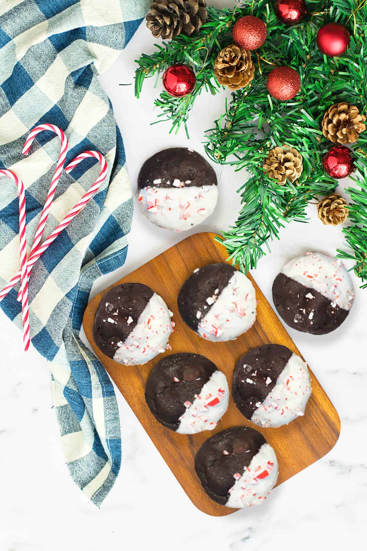 Chocolate mint cookies on wooden board with greenery.