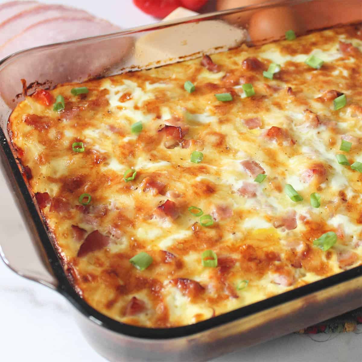 Partial view of baked hashbrown breakfast casserole on white table.