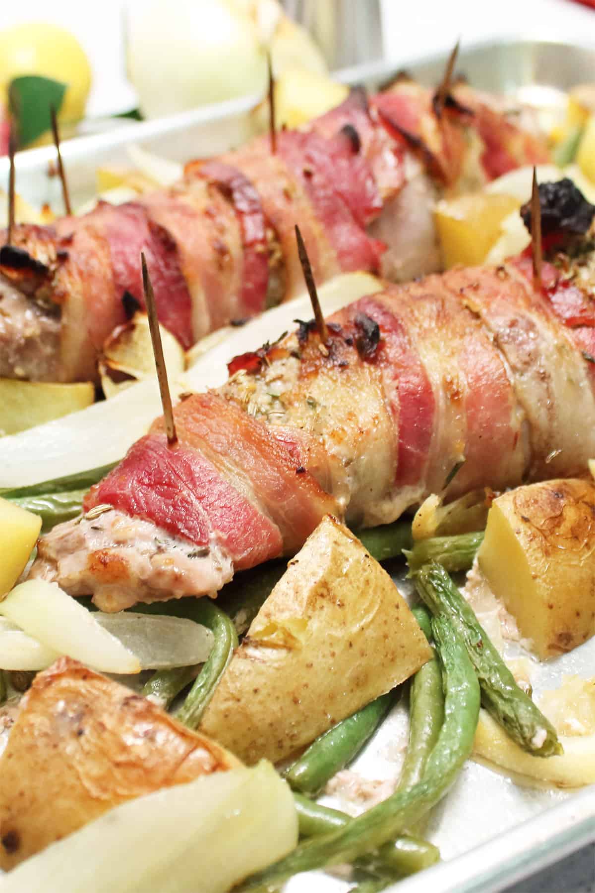 Closeup of roasted prok tenderloin on sheet pan with vegetables.