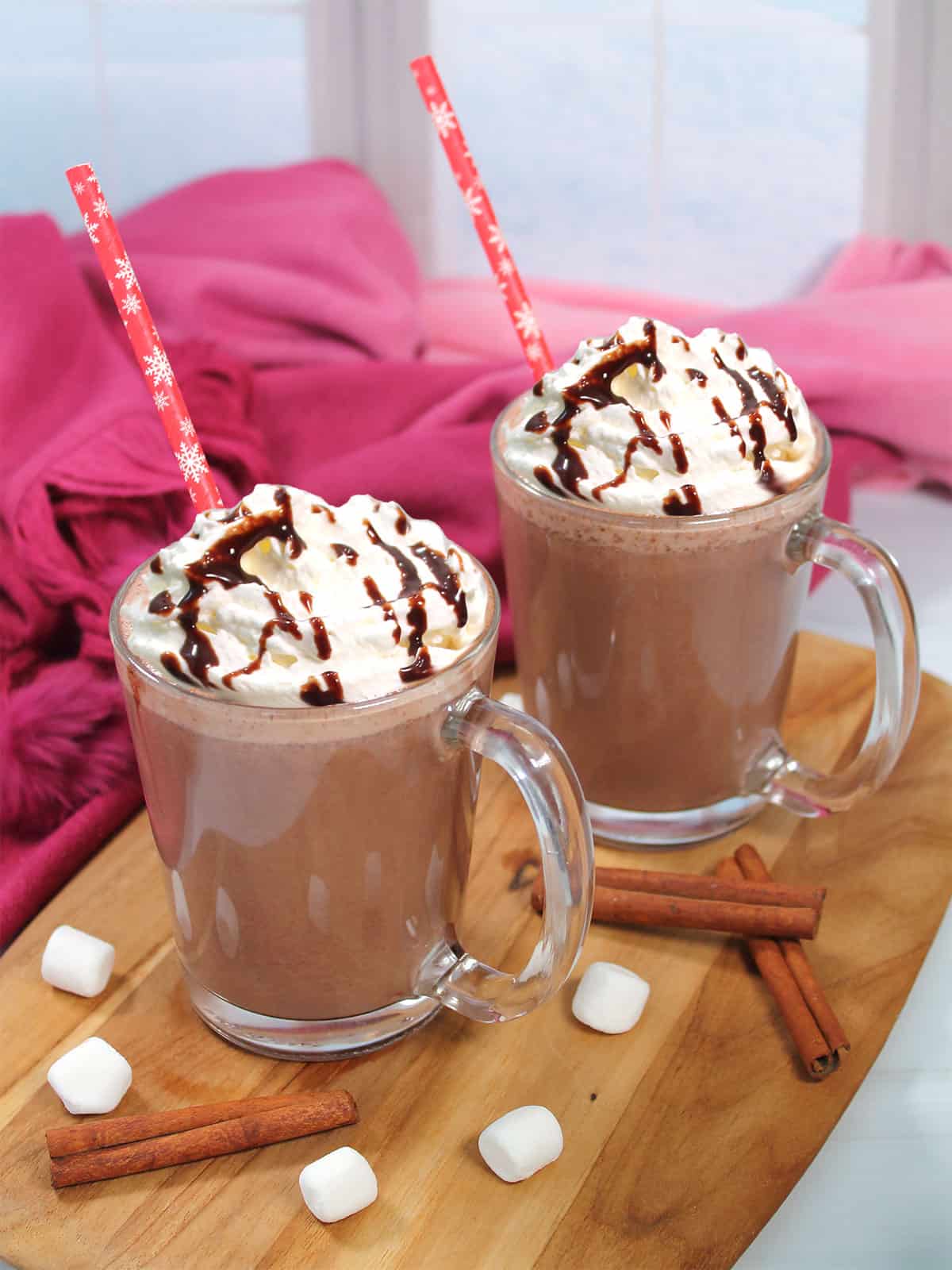 Two mugs of Spiked Mexican Hot Chocolate with straws.