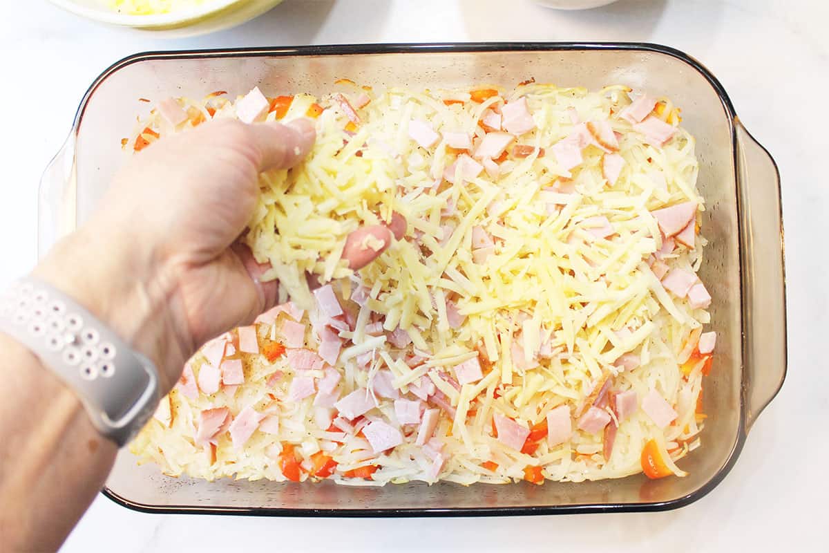Sprinkling ham and cheese over potato layer.