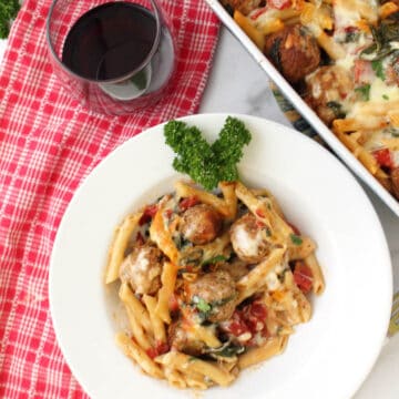 Overhead of serving in white bowl with casserole and wine glass beside it.