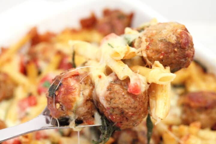 Serving spoon of baked meatball pasta.
