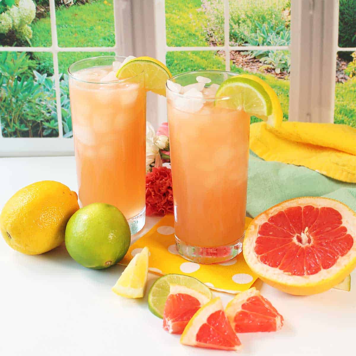 Two grapefruit cocktails amongst fruit.