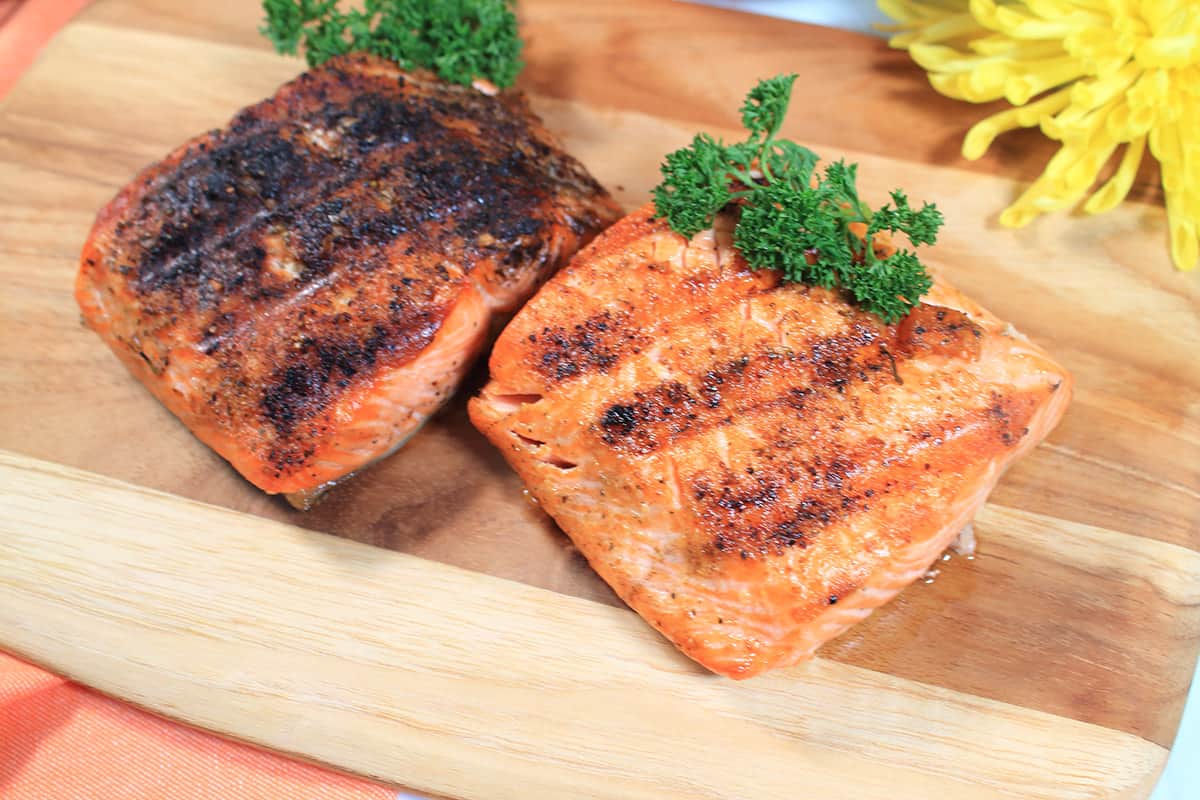 Closeup of grilled salmon on wooden board.