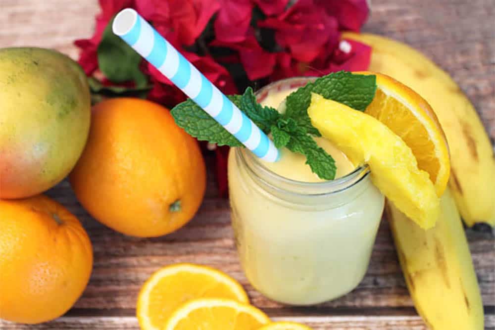 Overhead of smoothie surrounded by fruit wit a mint and mango garnish.