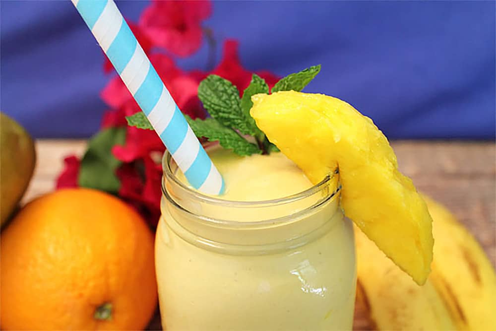 Closeup of smoothie in glass with turquoise striped straw.