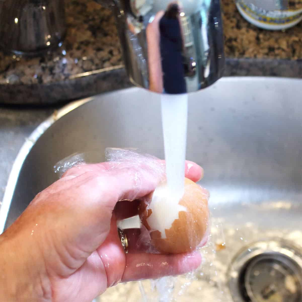 Egg under running water to peel.