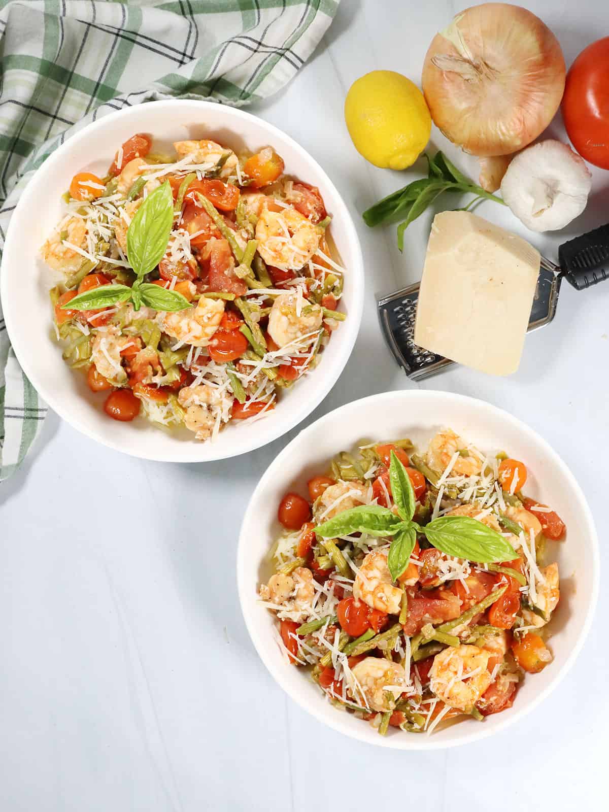 Two serving bowls of shrimp primavera over spaghetti squash.