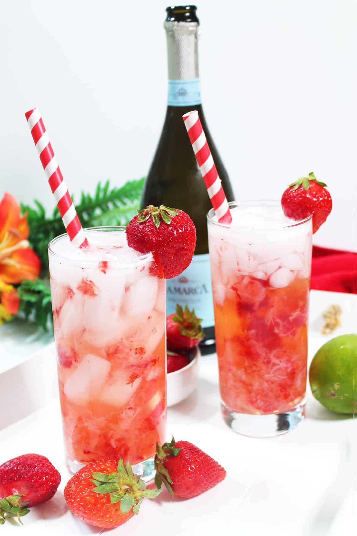 Bubbly rum cocktail with strawberries and bottle of prosecco.