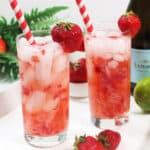 Two garnished cocktails on tray with Prosecco.