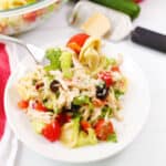 Bite of tortellini salad over plate.