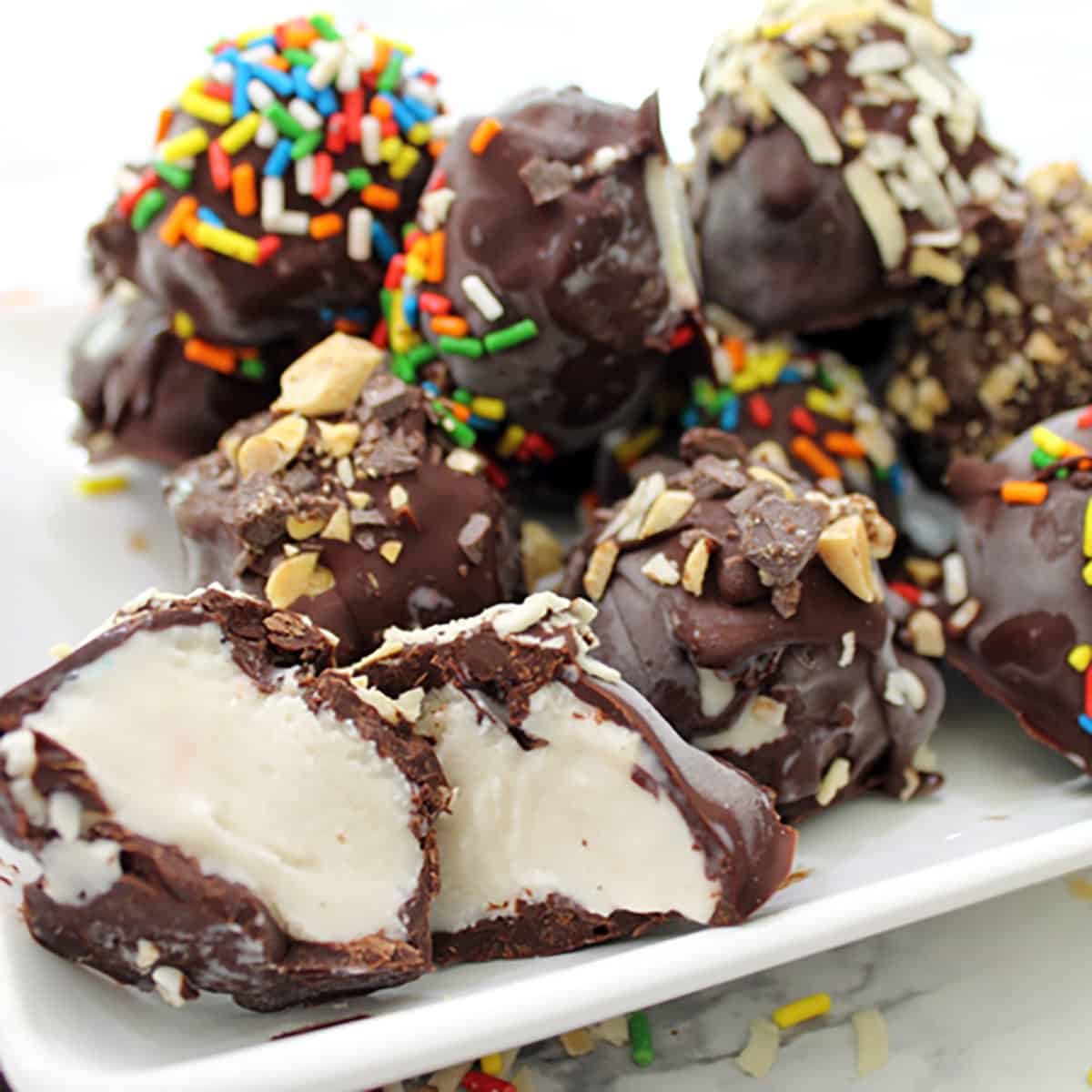 Plated chocolate covered ice cream with sprinkles on top.
