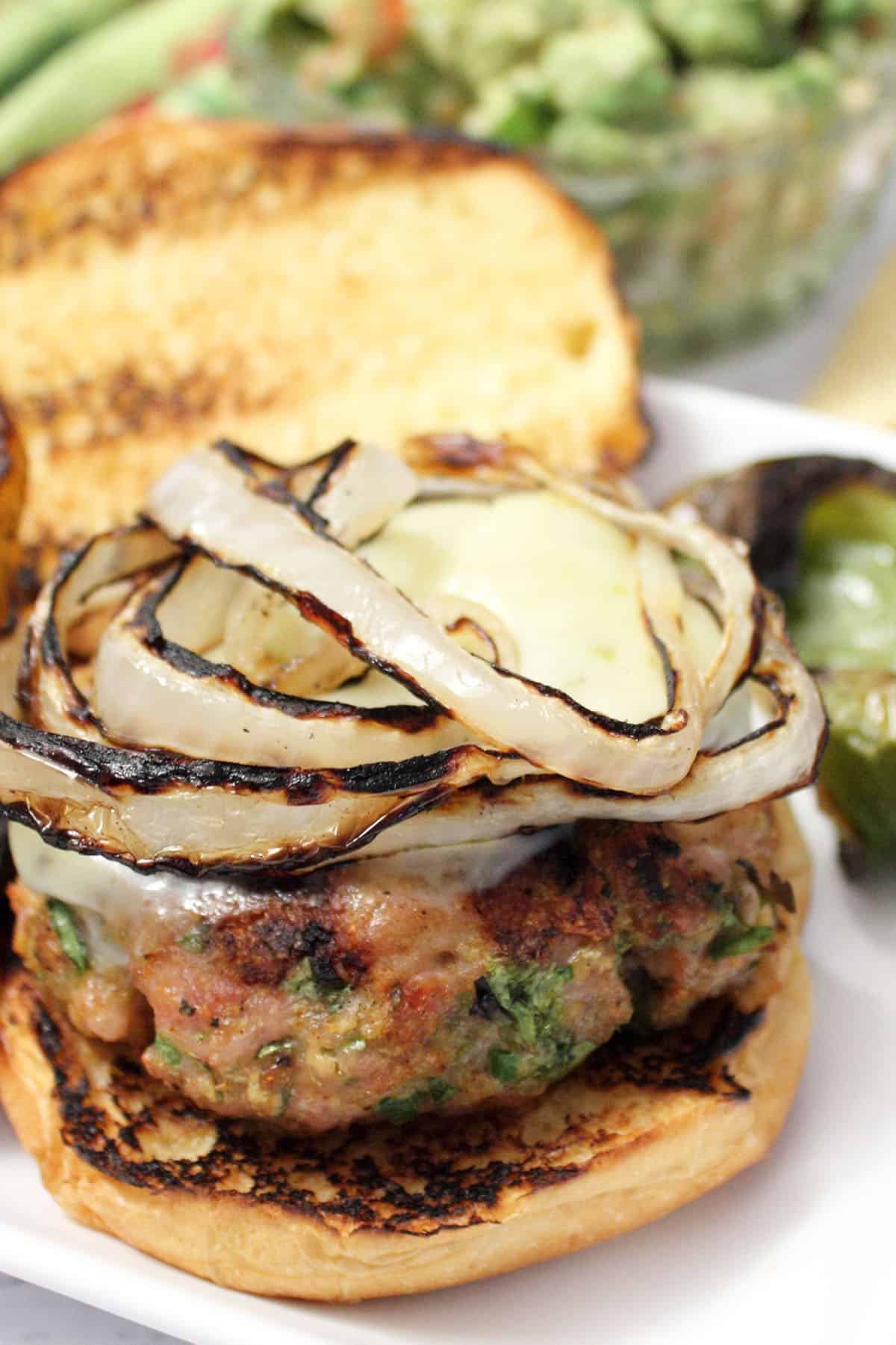 Closeup of burger on a toasted roll with topping of grilled onions.