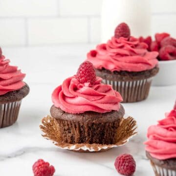 Chocolate cupcake with raspberry frosting with liner pulled back.