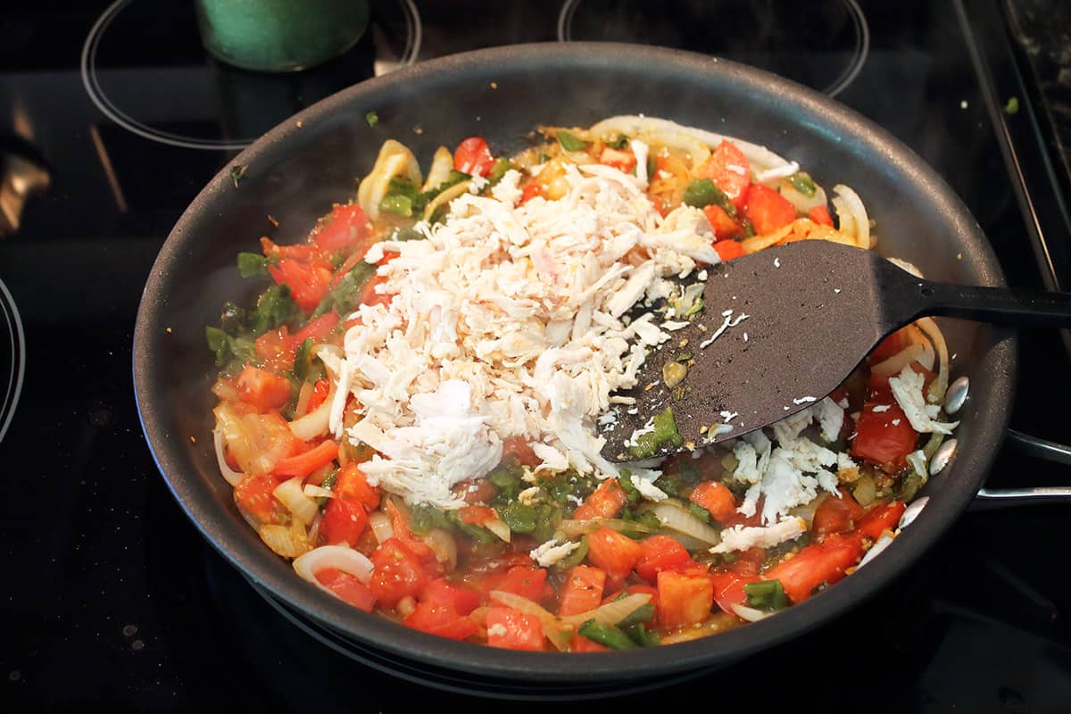 Adding chicken and green chiles to skillet.