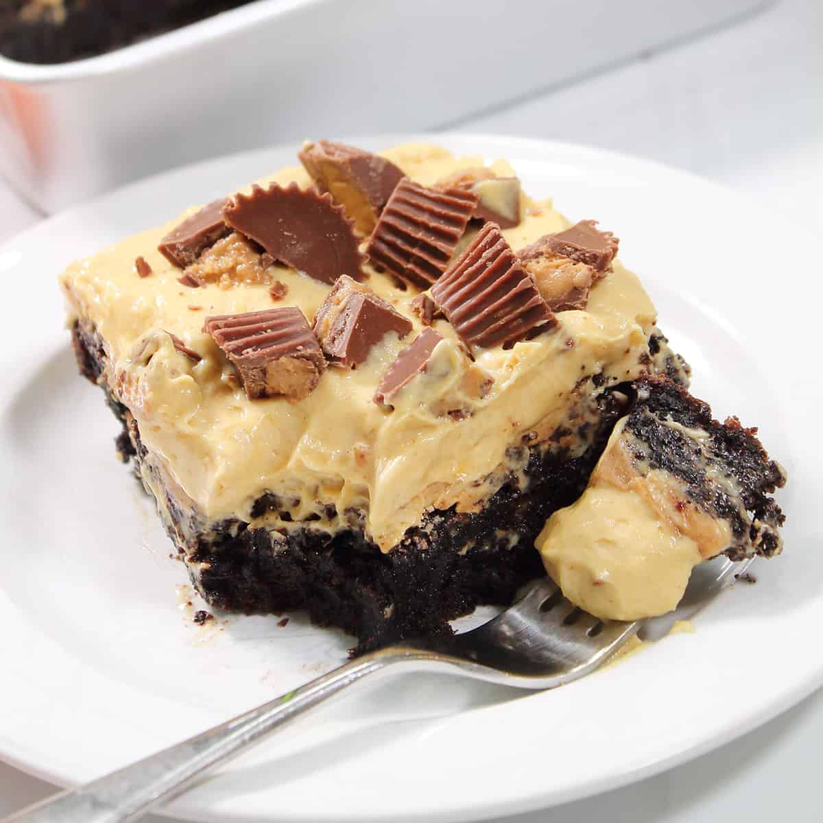Slice of chocolate poke cake with bite on fork.