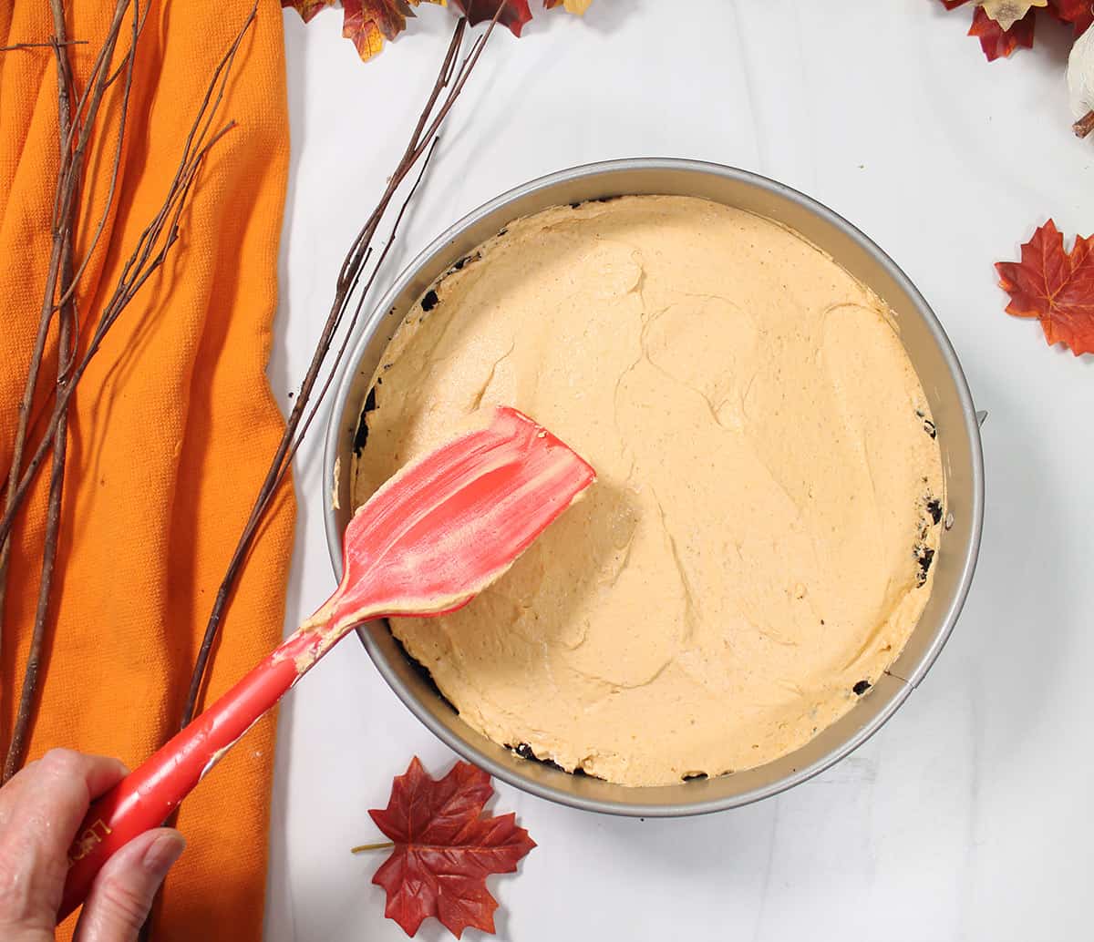 Smoothing top of cheesecake in springform pan.