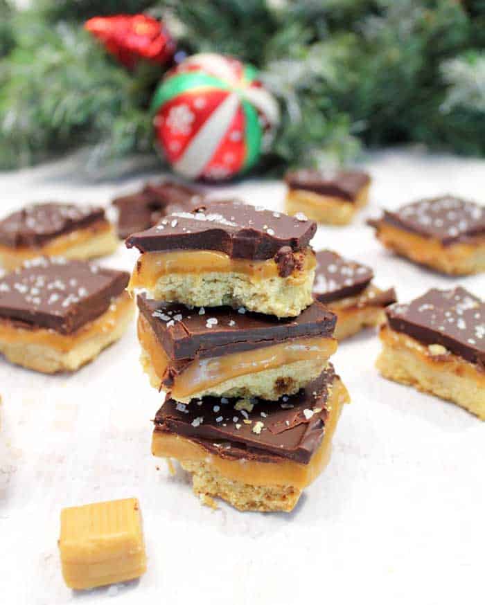 Stacked shortbread cookies on white table with caramels around.